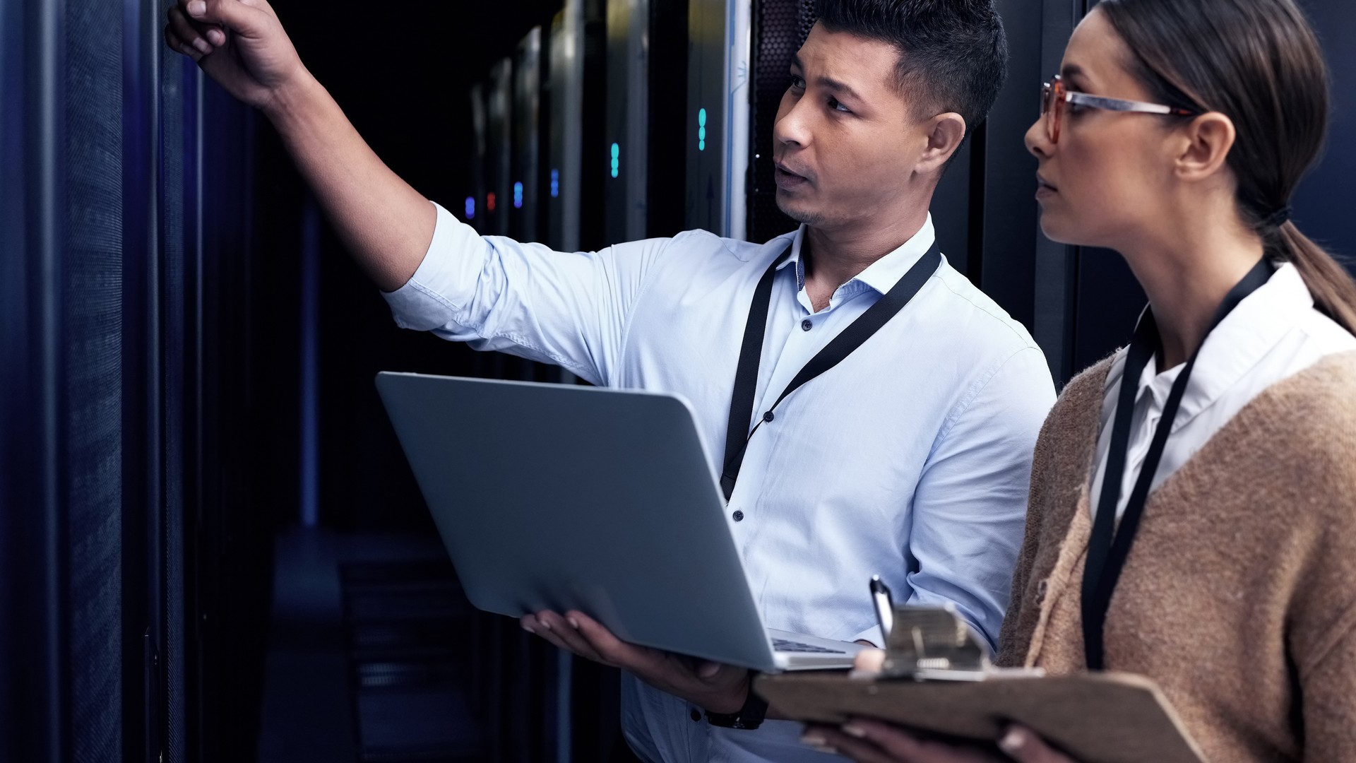 Technicians reviewing a laptop checklist for patch management in a server room