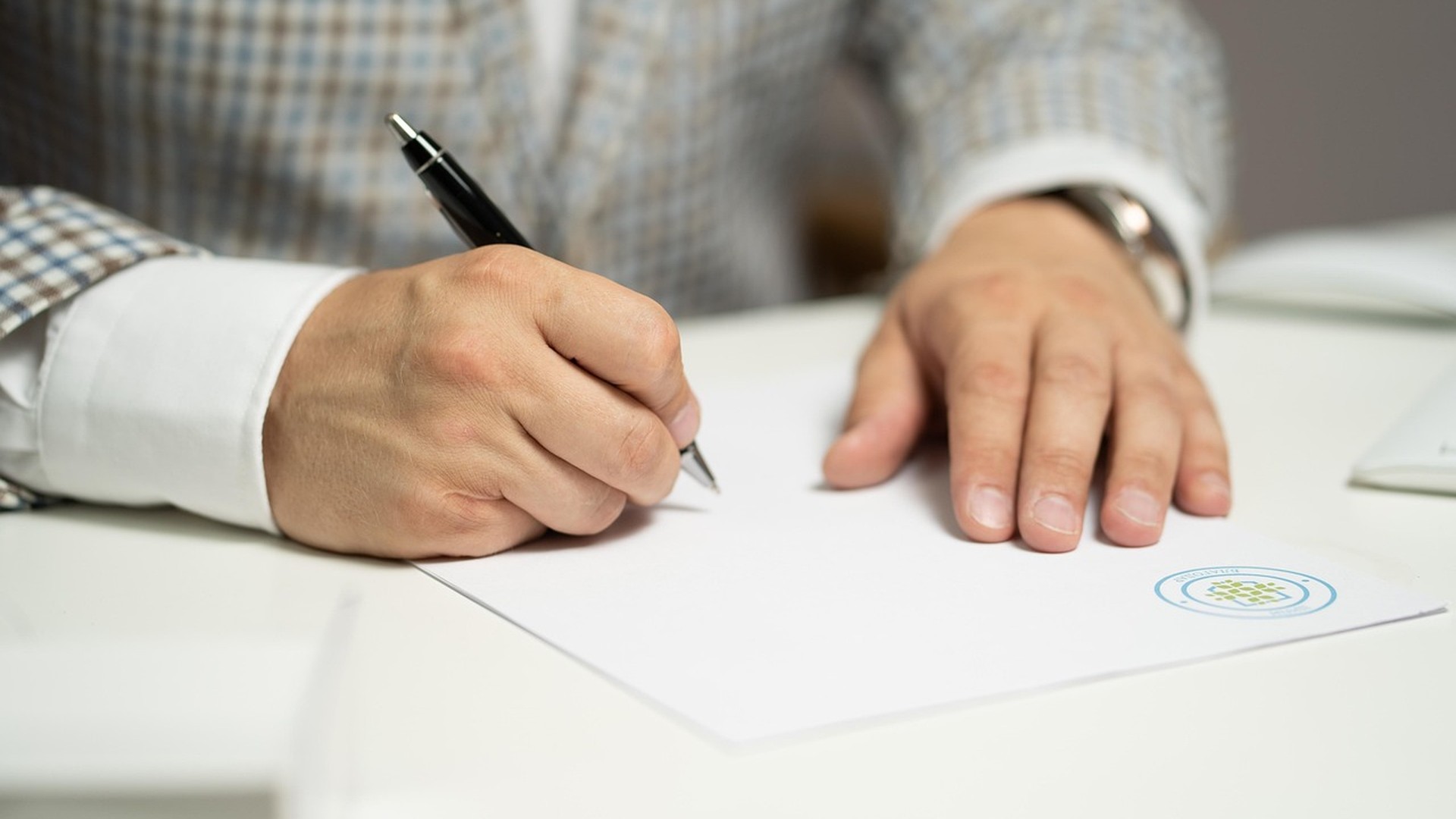 Business owner signing a contract with paperwork on a desk