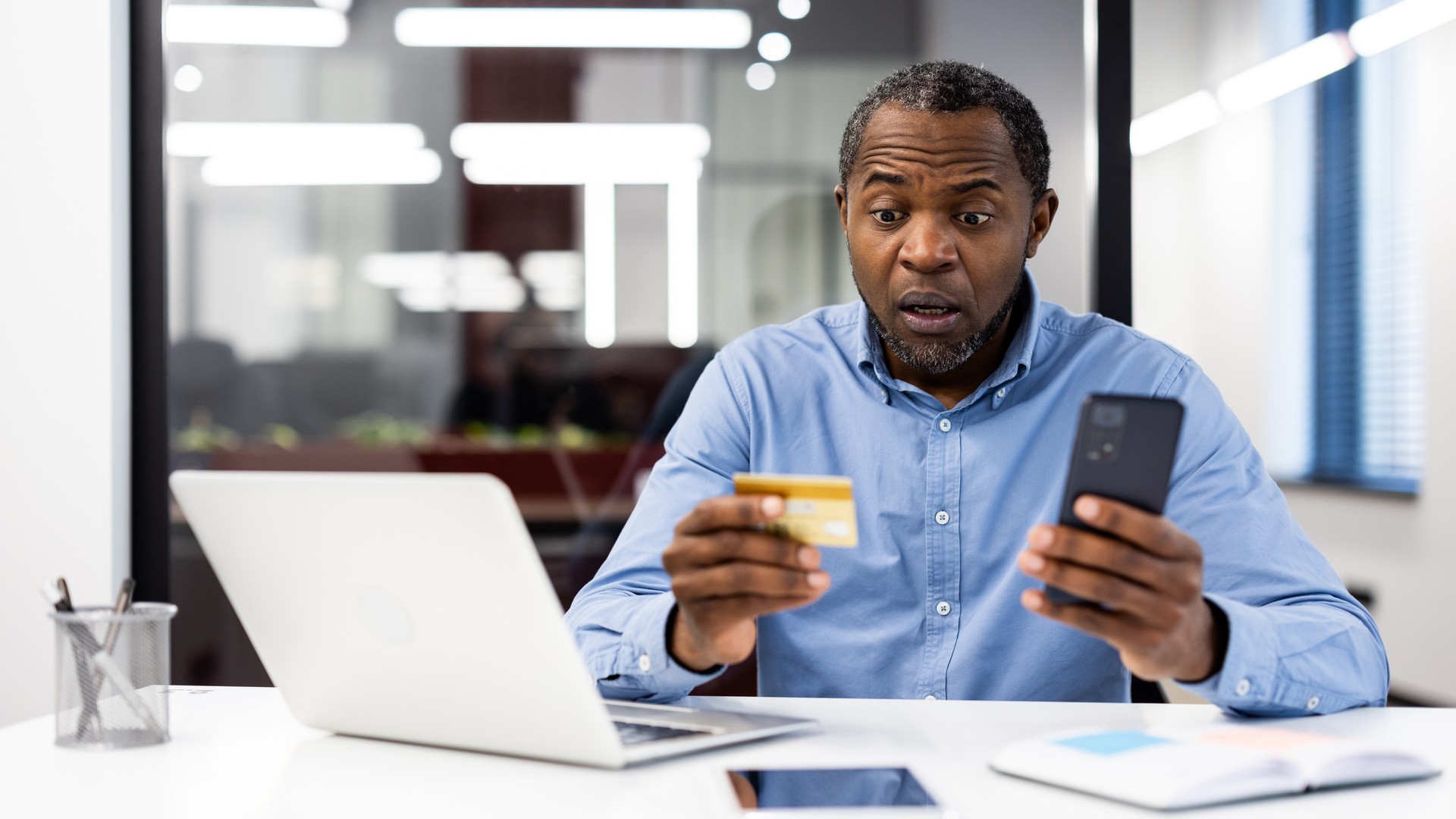 Office worker reviewing a suspicious phone payment for cybersecurity risk
