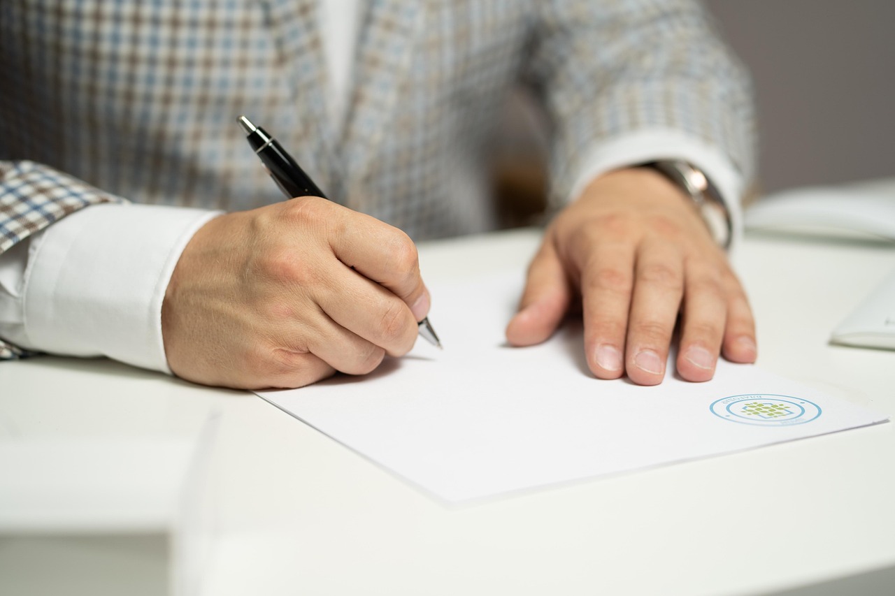 Business owner signing a contract with paperwork on a desk