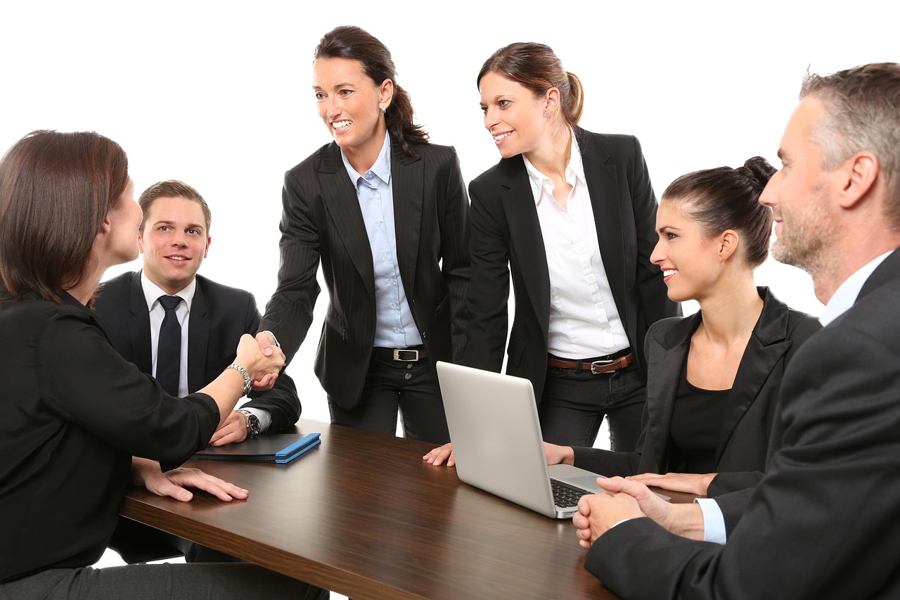 Two business professionals shaking hands over an open laptop
