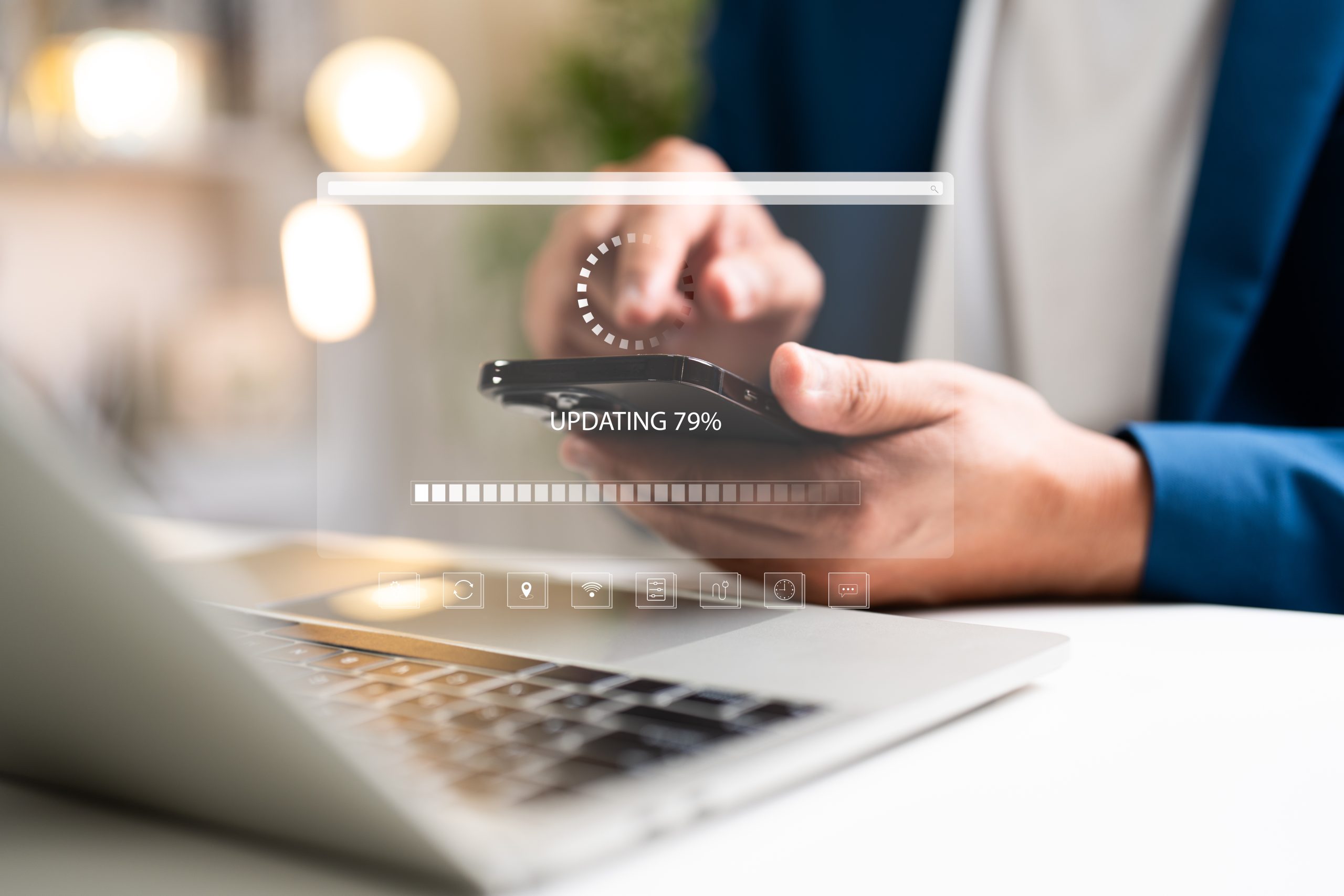 Hands using a smartphone beside a laptop with an Updating 79% progress graphic.