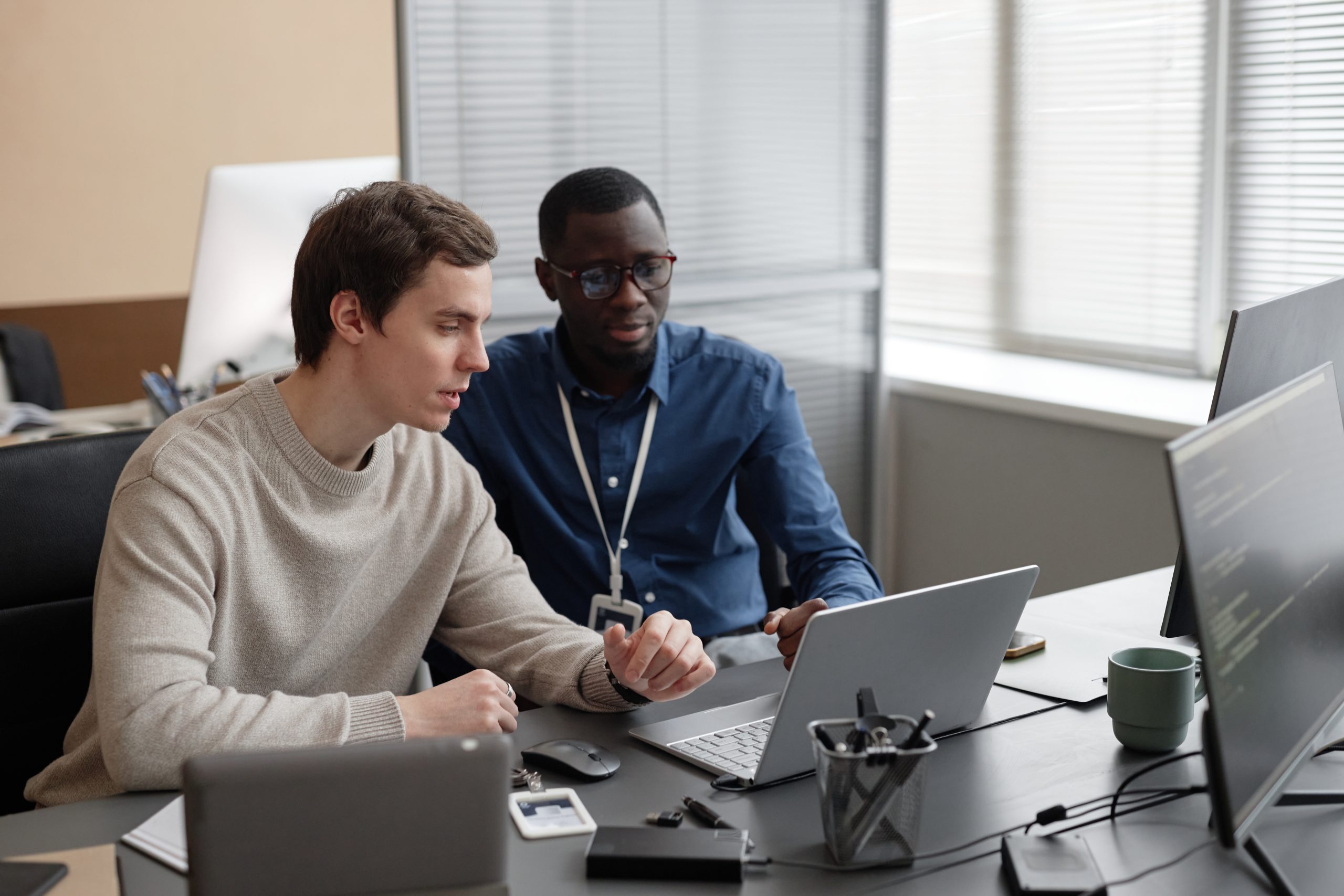 Two people looking at a laptop together at an office desk.
