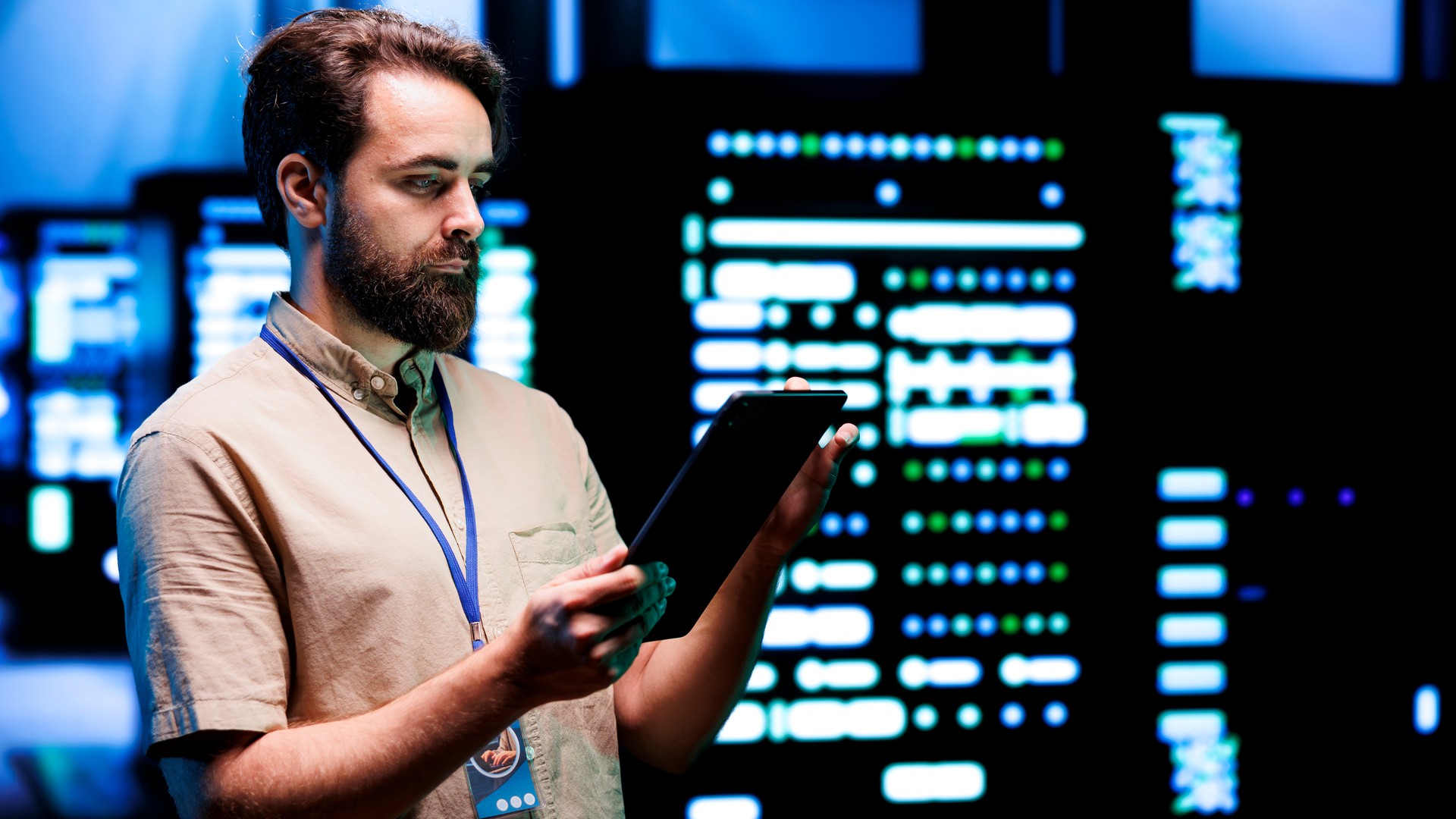 Person using a tablet in front of illuminated server equipment.
