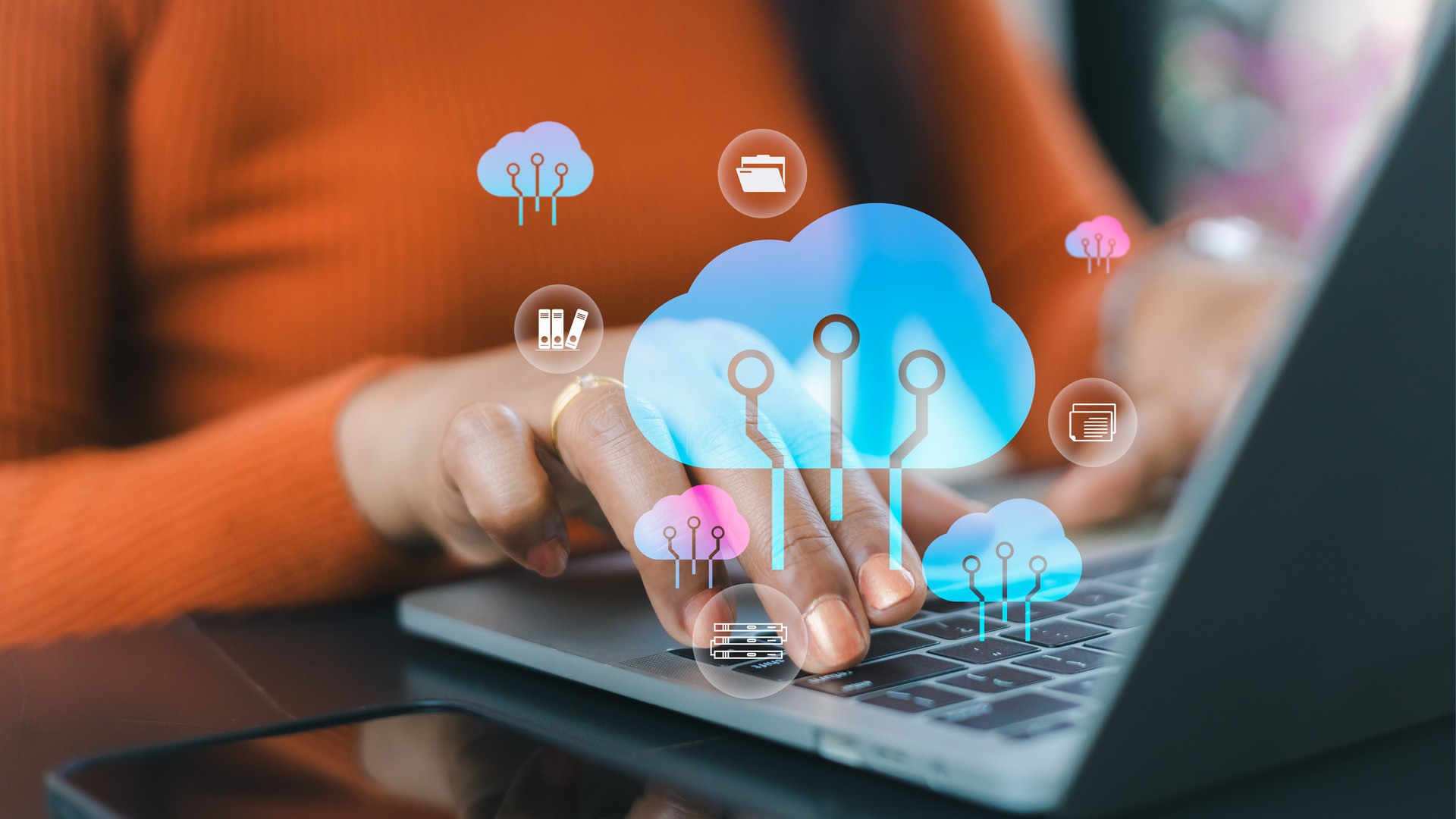Hands using a laptop with an overlaid blue cloud and connected application icons.