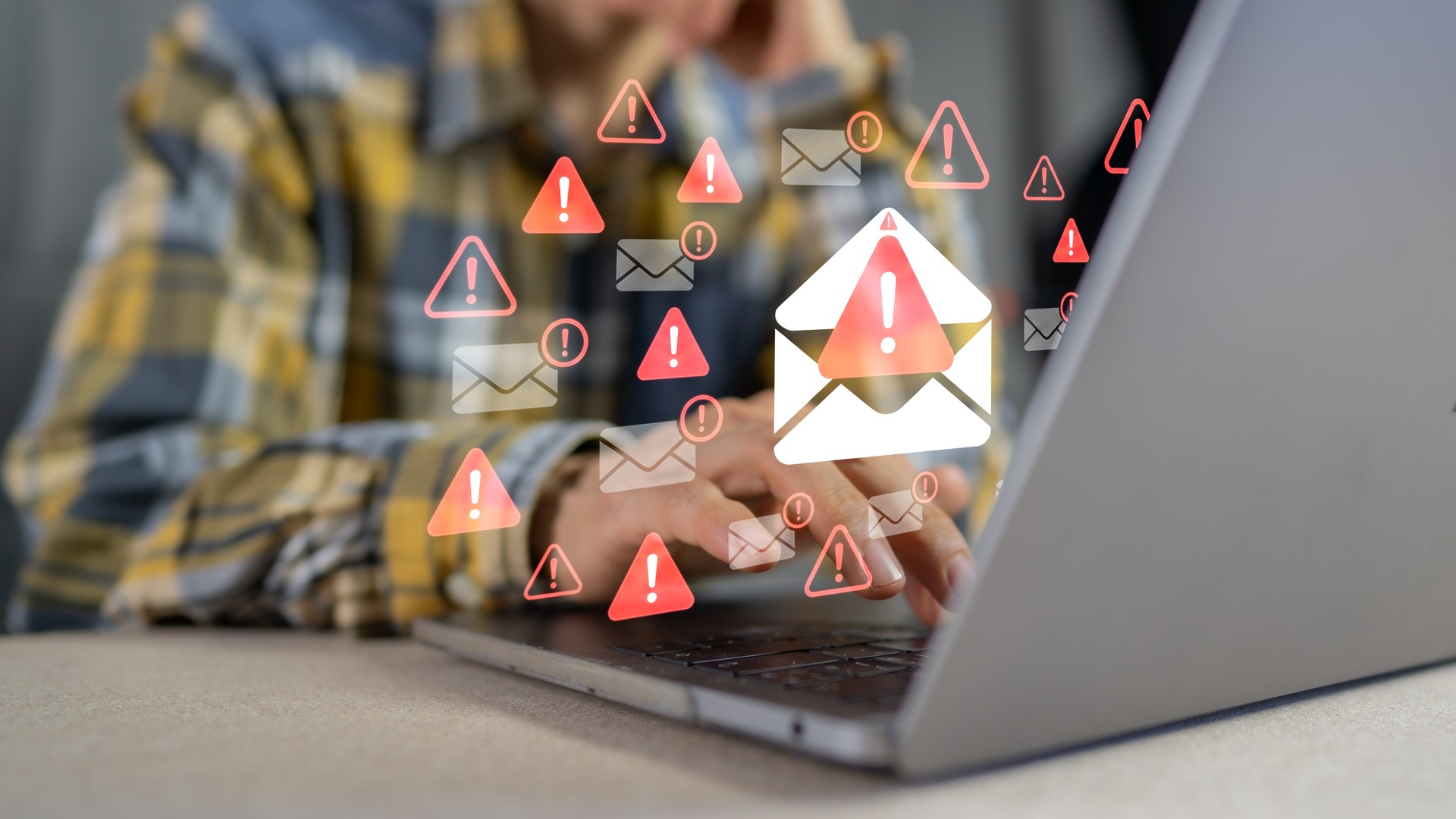 Laptop user with overlaid envelope icons and red warning triangles.