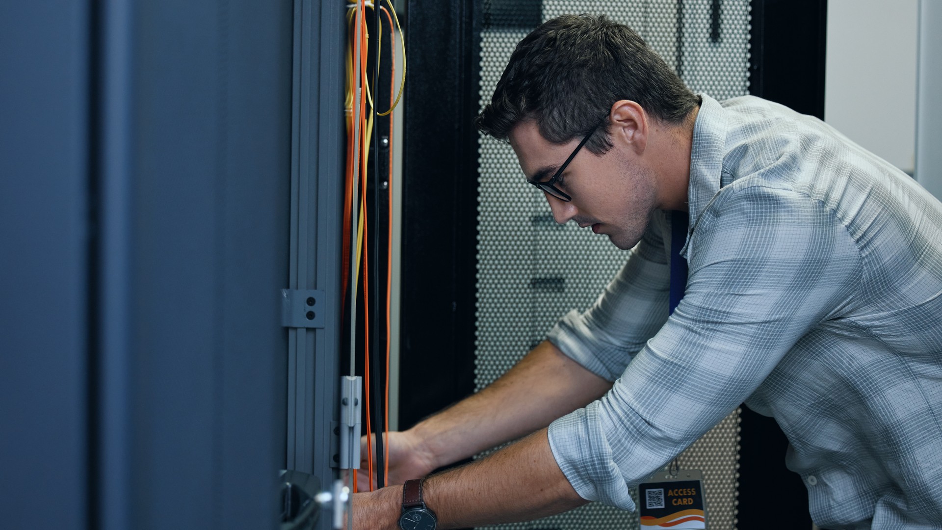 Man working with both hands inside an open equipment rack.