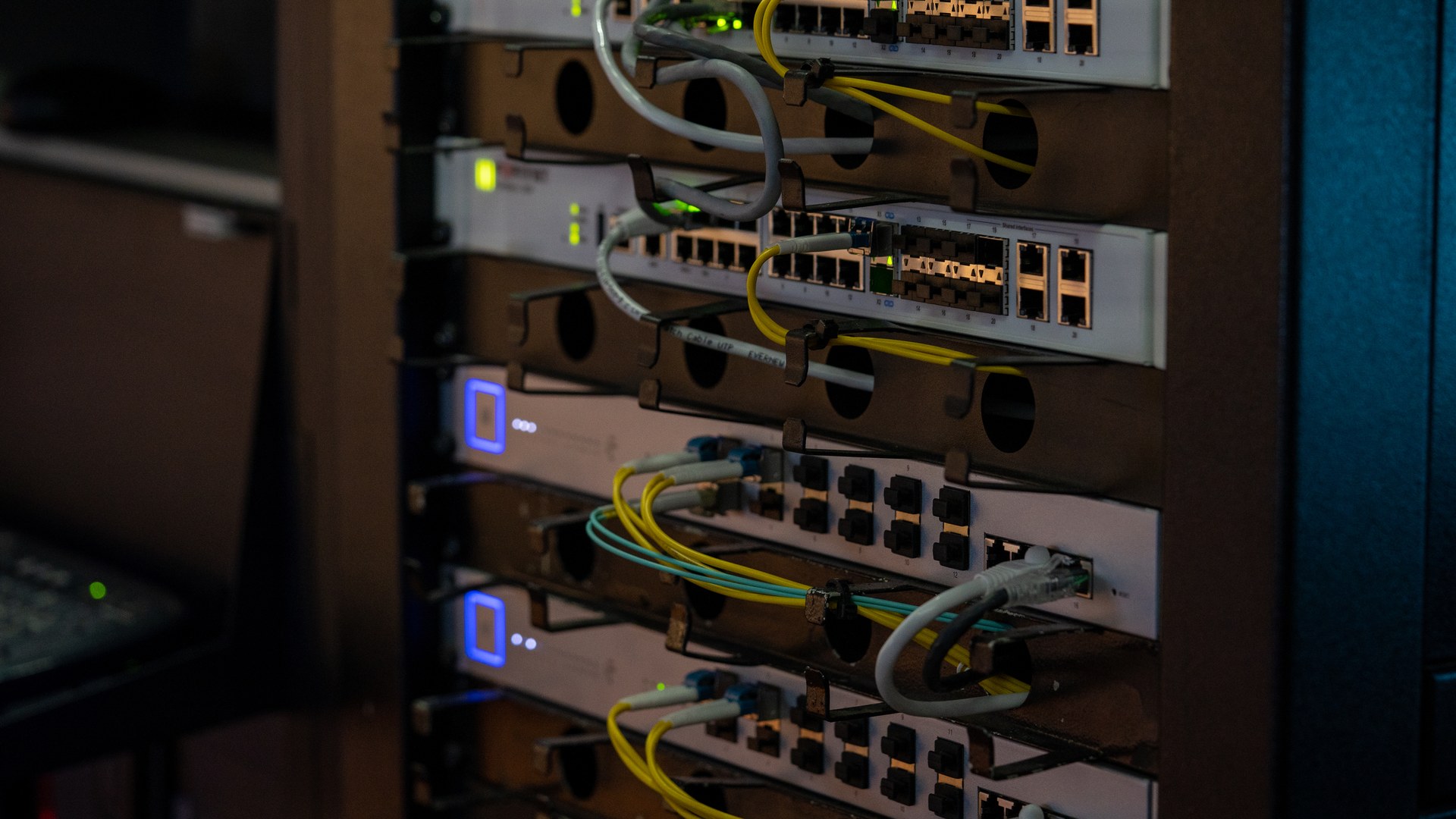 Rack-mounted network equipment with connected patch cables and illuminated status lights.